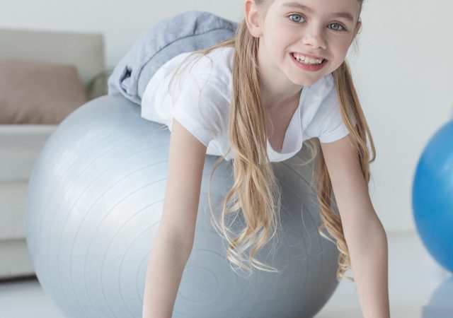 smiling mother and daughter lying on fit balls at home